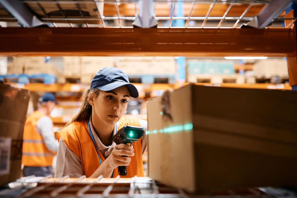 Female warehouse worker uses bar code reader while scanning