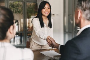Two employers sitting in office and shaking hand of young asian woman after successful negotiations or interview Standing Out as a Job Candidate