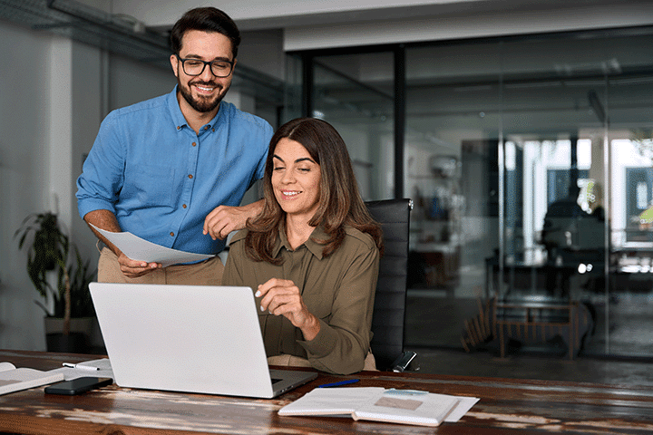 Two happy busy professional business people using laptop technology working together in office fractional hiring